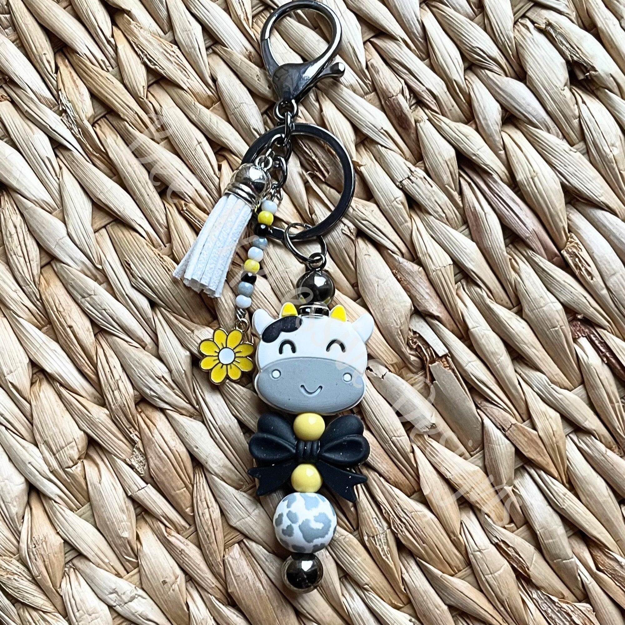 Beaded COW keychain with a black bow! HANDMADE with a lobster or swivel clasp, silicone beads, beaded tassel with a daisy charm!