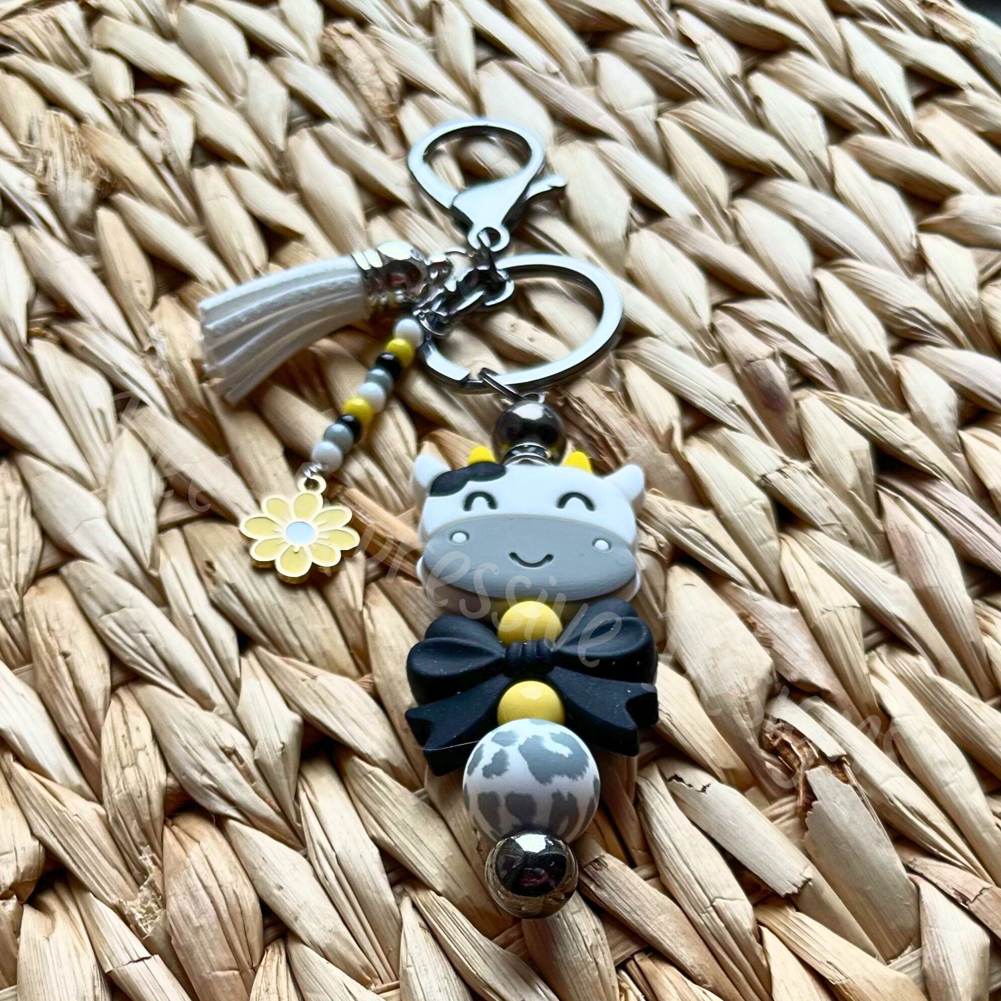 Beaded COW keychain with a black bow! HANDMADE with a lobster or swivel clasp, silicone beads, beaded tassel with a daisy charm!