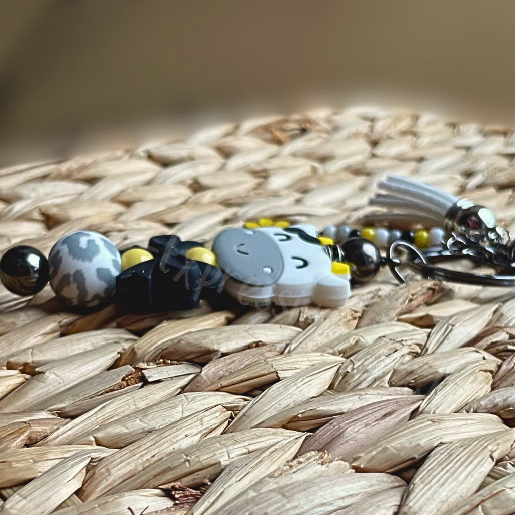 Beaded COW keychain with a black bow! HANDMADE with a lobster or swivel clasp, silicone beads, beaded tassel with a daisy charm!