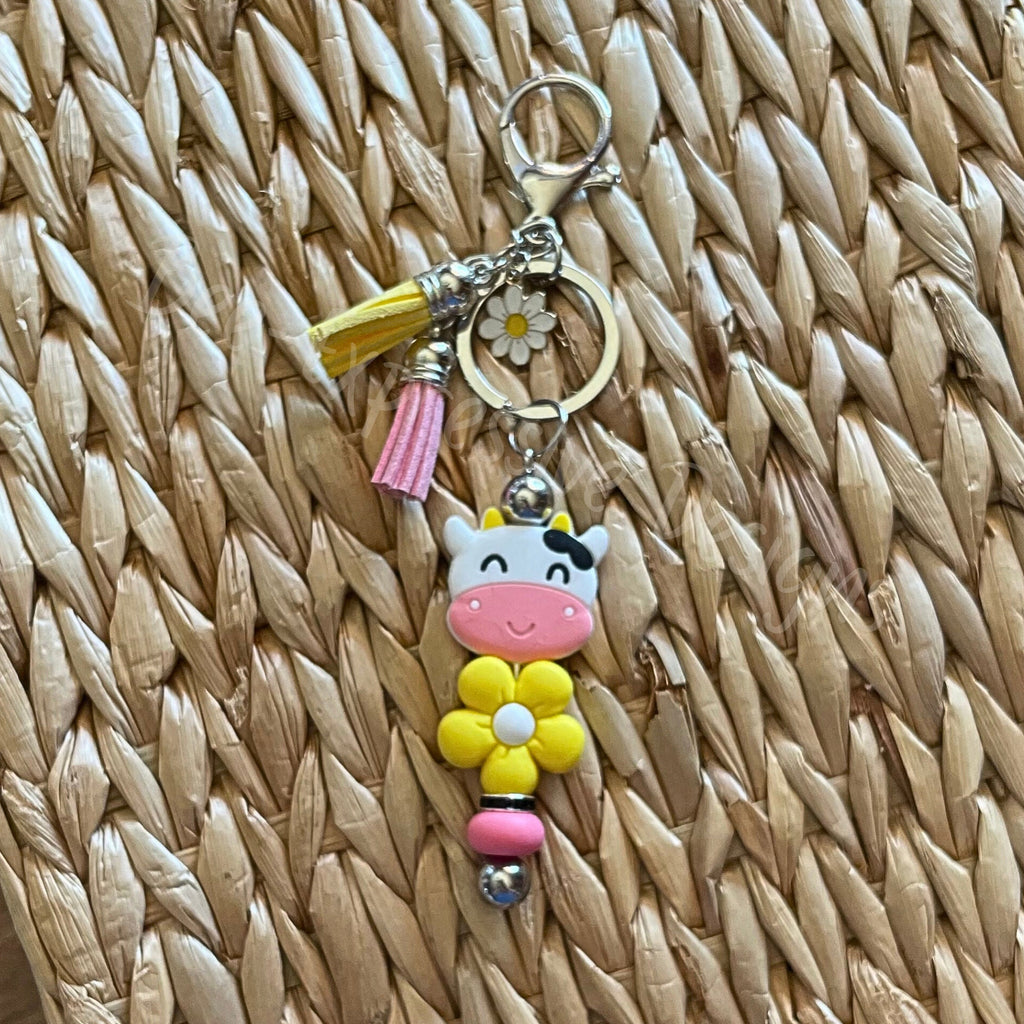 Handmade, fun yellow daisy and cow focal beaded keychain! Silver, lobster claw clasp, interchangeable, rhinestone bead, daisy charm, tassels