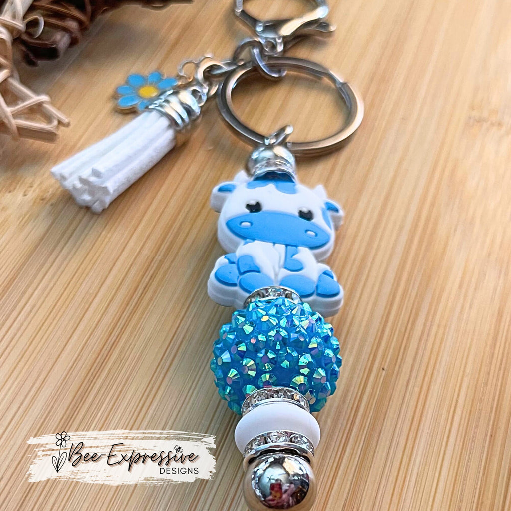 Beautiful handmade baby blue cow keychain with a 20mm rhinestone bead and a daisy charm!
