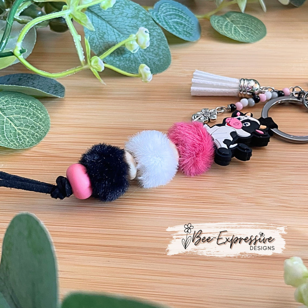 Adorable, handmade, black and white, bull cow keychain! Furry beads, silicone lentil spacer beads, beaded tassel with metal flower charm