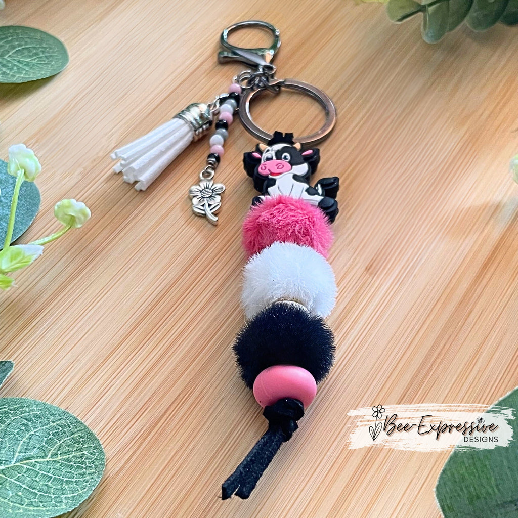 Adorable, handmade, black and white, bull cow keychain! Furry beads, silicone lentil spacer beads, beaded tassel with metal flower charm