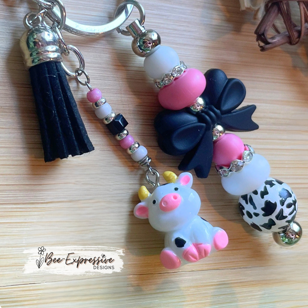 Adorable, handmade cow/bull keychain!  Lobster claw clasp, silicone bow, beaded tassel, cow charm, rhinestones, lentils, silver beads