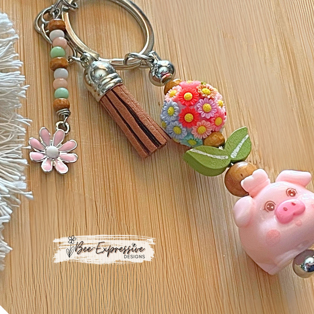 Adorable, handmade, pink pig metal keychain with multi floral bead!  Lobster claw clasp, bead bar, wood beads, beaded tasse pink daisy charm