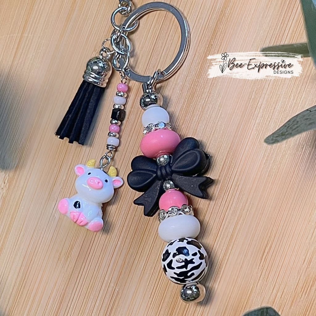 Adorable, handmade cow/bull keychain!  Lobster claw clasp, silicone bow, beaded tassel, cow charm, rhinestones, lentils, silver beads