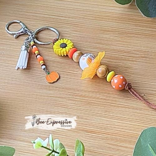 HELLO FALL, keychain!  Lobster clasp, cord, wood beads, acrylic leaves, silicone sunflower, polka dot, beaded tassel with a pumpkin charm!