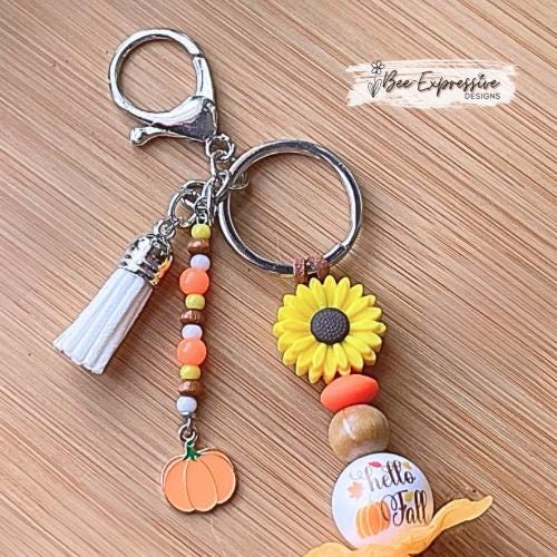 HELLO FALL, keychain!  Lobster clasp, cord, wood beads, acrylic leaves, silicone sunflower, polka dot, beaded tassel with a pumpkin charm!