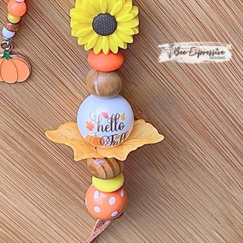 HELLO FALL, keychain!  Lobster clasp, cord, wood beads, acrylic leaves, silicone sunflower, polka dot, beaded tassel with a pumpkin charm!