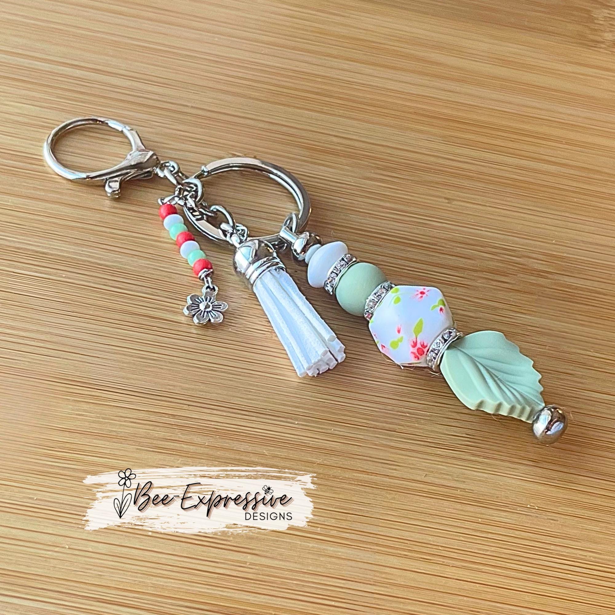 Beaded, handmade keychain with floral hexagon bead and silicone leaf! Lobster clasp, rhinestone spacers, beaded tassel with a flower charm!