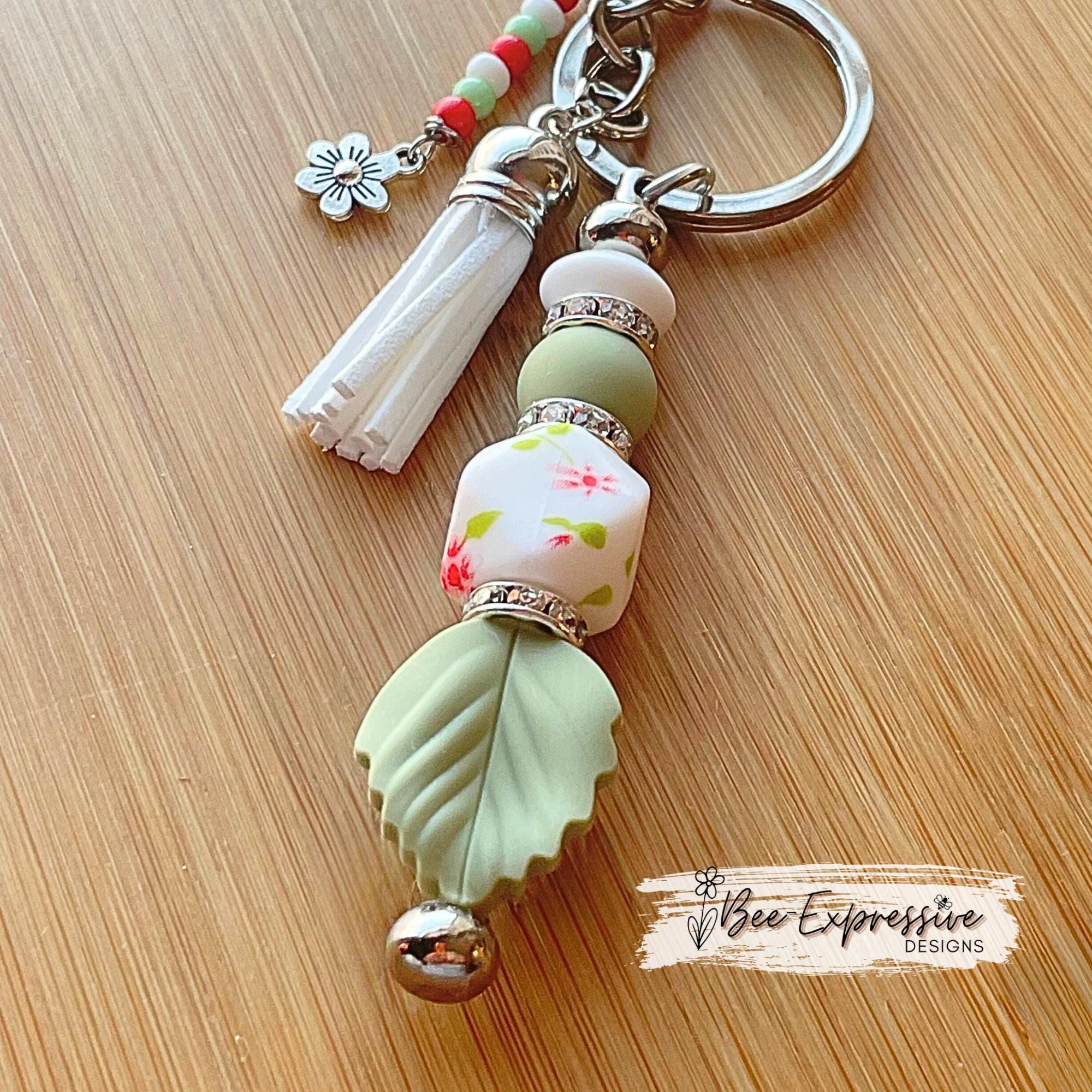 Beaded, handmade keychain with floral hexagon bead and silicone leaf! Lobster clasp, rhinestone spacers, beaded tassel with a flower charm!