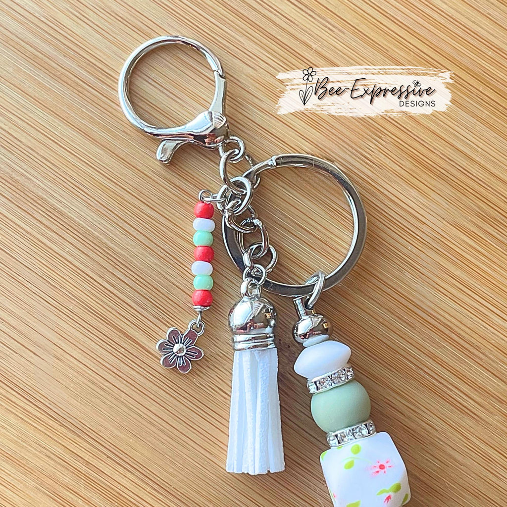 Beaded, handmade keychain with floral hexagon bead and silicone leaf! Lobster clasp, rhinestone spacers, beaded tassel with a flower charm!