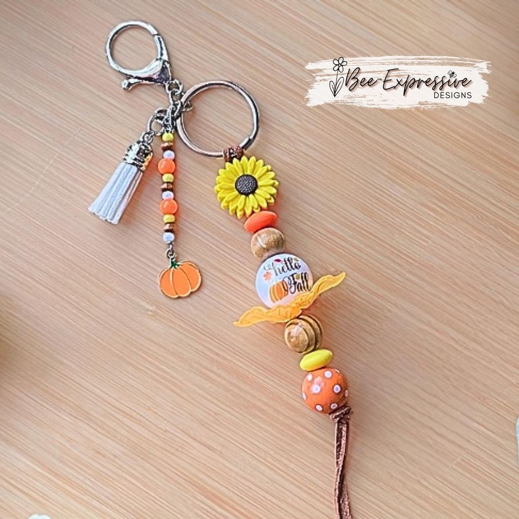 HELLO FALL, keychain!  Lobster clasp, cord, wood beads, acrylic leaves, silicone sunflower, polka dot, beaded tassel with a pumpkin charm!